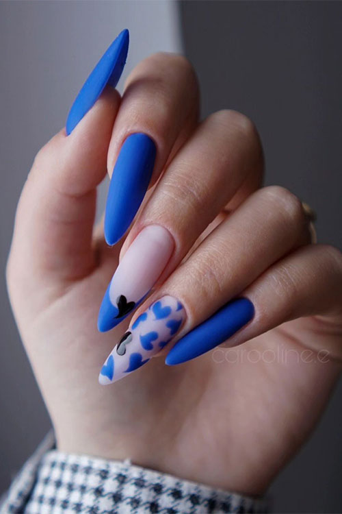 Long stiletto matte blue Valentine's Day nails with a blue French accent nail adorned with a tiny black heart shape