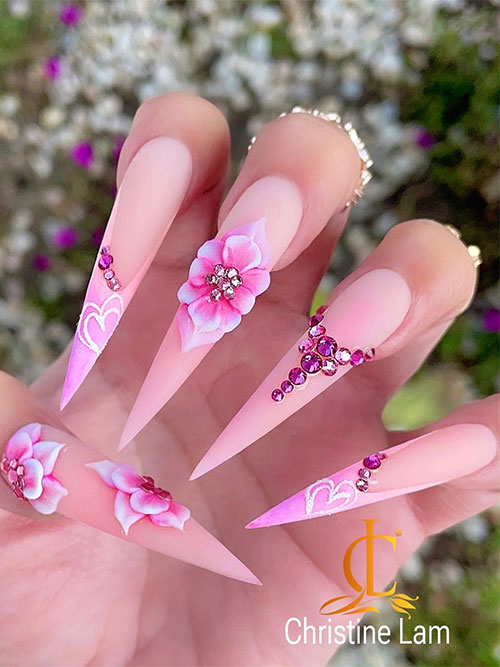 Long stiletto-shaped matte nude pink spring nails adorned with flowers and rhinestones besides, two pastel pink French nails