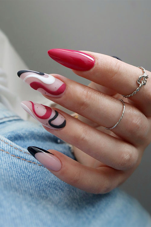 Red and black nails with two nude accent nails adorned with white, black, and red swirls