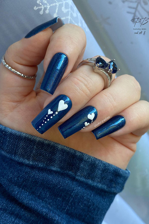 Shimmer navy blue Valentine's Day nails with two nails adorned with white dots and hearts