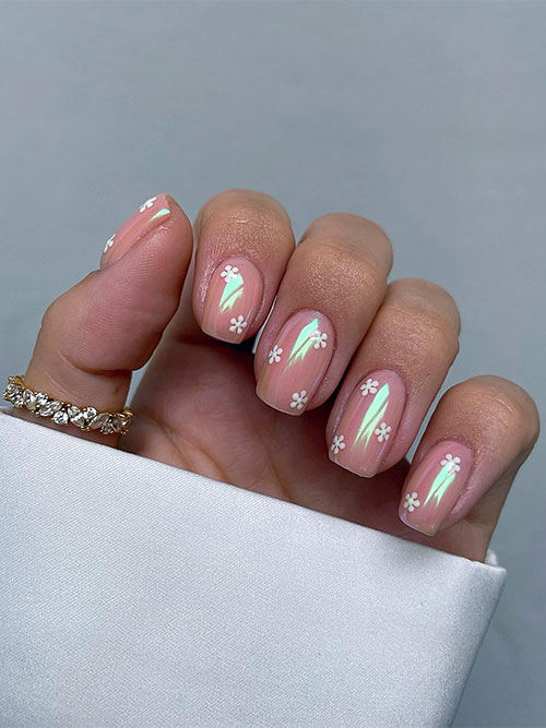 Simple flower spring nails feature tiny daisy flowers on a nude base color adorned with a chrome powder effect