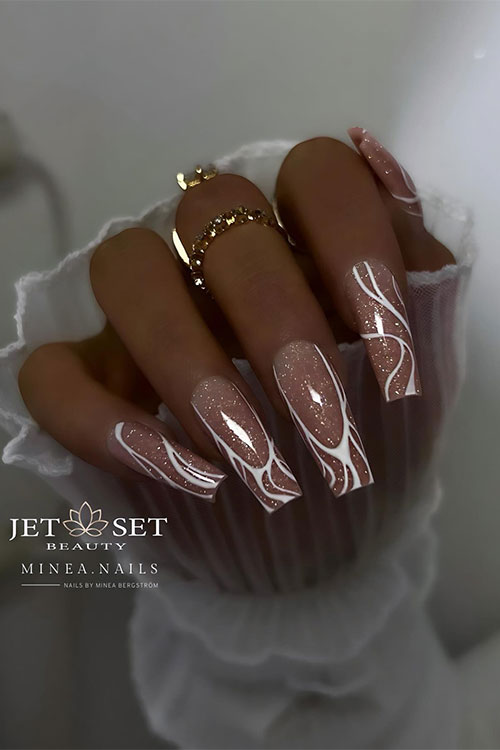 Stunning coffin glossy nude nails with a touch of gold glitter and white swirls