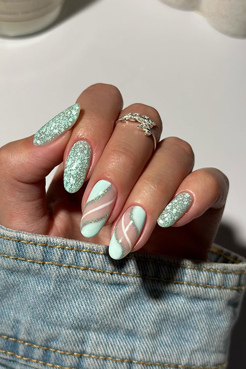 Gel mint green spring nails are covered with particles of various sizes and two mint green nails adorned with swirls