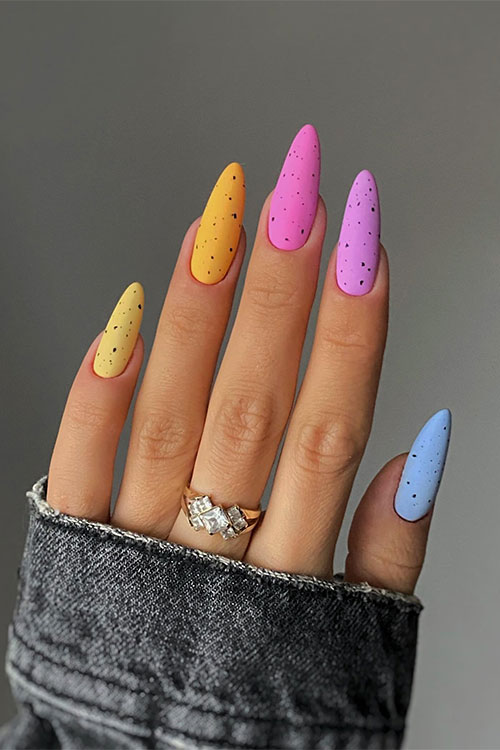 Long almond-shaped matte multicolored Easter nails with black speckles create cute Easter egg nails