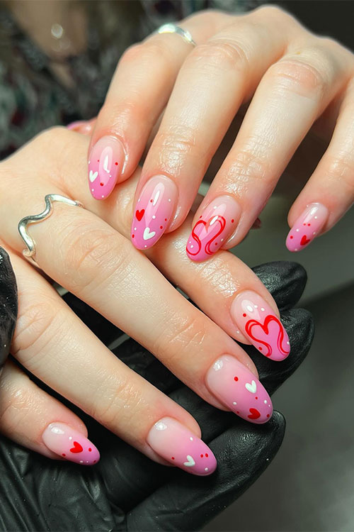 Almond-shaped Valentine’s Day nails pink ombre adorned with red and white dots and hearts