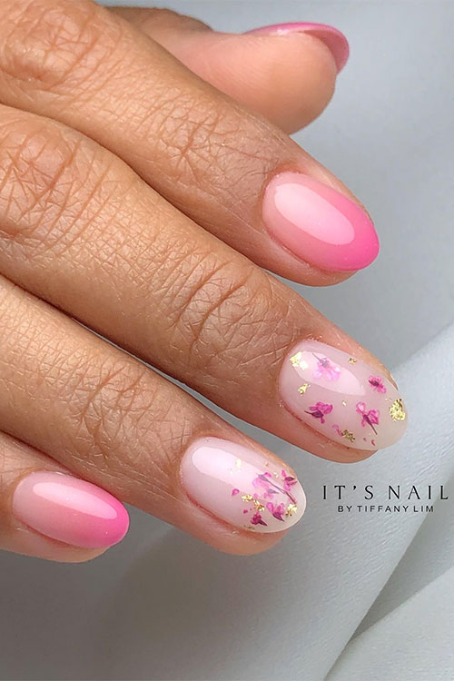 Short pink ombre nails almond shaped with two accent milky white nails adorned with pink dry flowers and gold foil patches