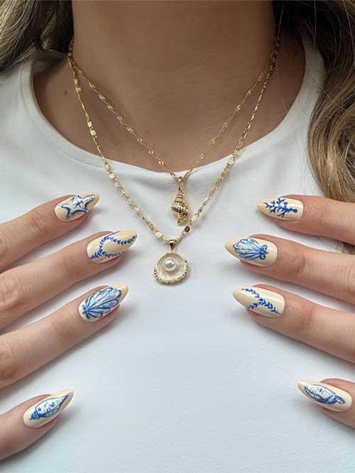 Elegant seashell-inspired nails with blue designs on a beige base, perfect for a chic seaside look. Elegant seashell-inspired nails with blue designs on a beige base, perfect for a chic seaside look.