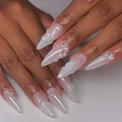Elegant seashell-inspired stiletto nails with a pearlescent base, adorned with 3D seashells, pearls, and rhinestones. Elegant seashell-inspired stiletto nails with a pearlescent base, adorned with 3D seashells, pearls, and rhinestones.