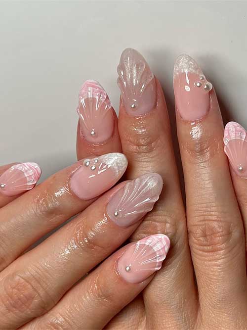 Elegant seashell nails with a soft pink base, featuring 3D seashell designs and pearl accents for a coastal charm. Elegant seashell nails with a soft pink base, featuring 3D seashell designs and pearl accents for a coastal charm.
