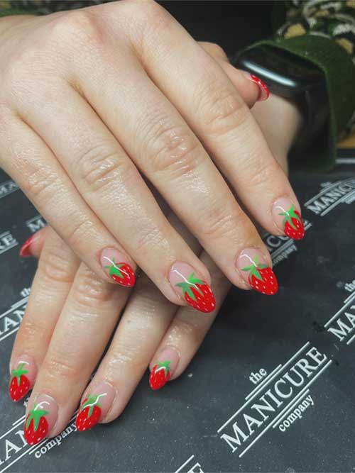 French tip strawberry nails on a nude base, featuring white tips and red strawberries with green leaves for a playful, chic look. French tip strawberry nails on a nude base, featuring white tips and red strawberries with green leaves for a playful, chic look.