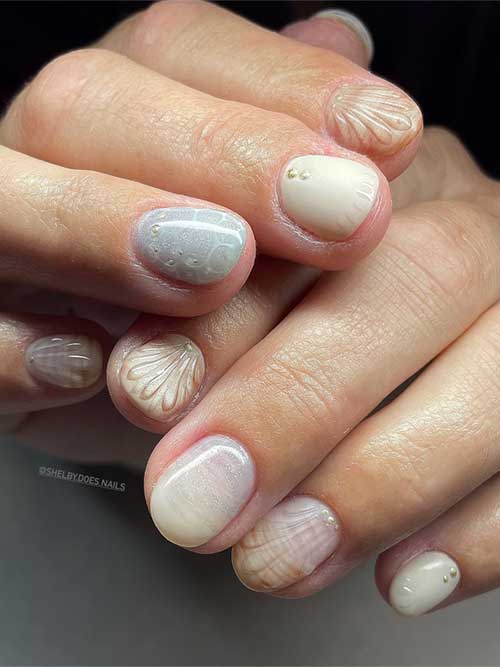 Seashell-inspired nails with neutral and pearlescent shades, featuring intricate designs and gold accents for a chic look. Seashell-inspired nails with neutral and pearlescent shades, featuring intricate designs and gold accents for a chic look.