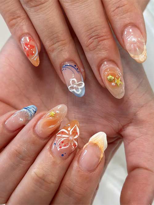 Seashell nails with starfish designs on a clear base, featuring soft blues, oranges, gold stars, and pearls for a summer vibe. Seashell nails with starfish designs on a clear base, featuring soft blues, oranges, gold stars, and pearls for a summer vibe.