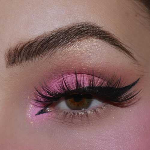 Vibrant pink eyeshadow with black winged eyeliner and gold glitter creates a striking, playful makeup look for any event. Vibrant pink eyeshadow with black winged eyeliner and gold glitter creates a striking, playful makeup look for any event.
