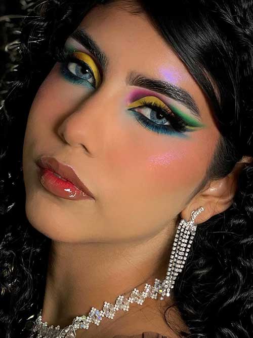 A vibrant eyeshadow look with rainbow hues enhances blue eyes, paired with a dewy complexion and glossy red lips. A vibrant eyeshadow look with rainbow hues enhances blue eyes, paired with a dewy complexion and glossy red lips.