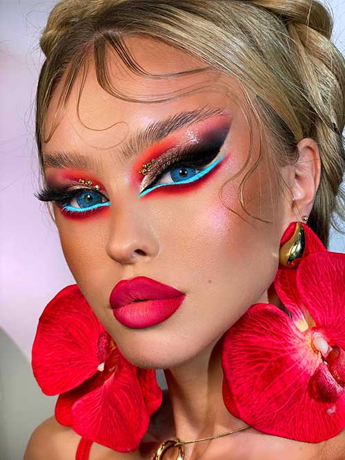 Bold eyeshadow for blue eyes look featuring red, pink, and black hues, with turquoise liner and golden rhinestones for glam. Bold eyeshadow for blue eyes look featuring red, pink, and black hues, with turquoise liner and golden rhinestones for glam.