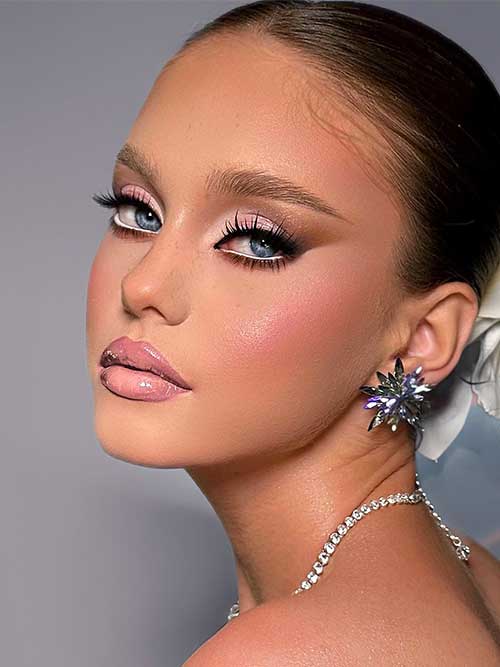 Bridal makeup featuring soft pink eyeshadow, brown winged liner, and glossy nude lips, enhancing blue eyes with elegance. Bridal makeup featuring soft pink eyeshadow, brown winged liner, and glossy nude lips, enhancing blue eyes with elegance.