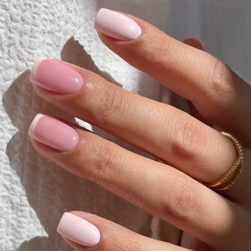 Chic short pastel pink nails with delicate French tips, blending soft pink and white for a sophisticated, feminine look.