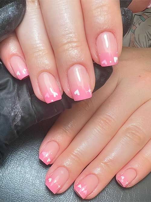 Stunning short pink ombre nails featuring a gradient from clear to soft pink, embellished with charming white heart designs. Stunning short pink ombre nails featuring a gradient from clear to soft pink, embellished with charming white heart designs.