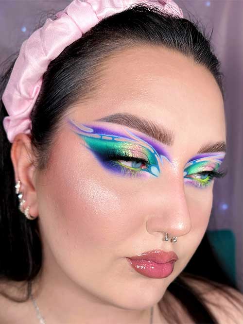 A vibrant purple and teal eyeshadow look features sharp wings, metallic highlights, and glossy lips for a bold, artistic style. A vibrant purple and teal eyeshadow look features sharp wings, metallic highlights, and glossy lips for a bold, artistic style.