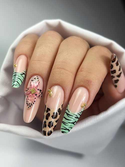 Animal print French manicure with nude base, leopard and zebra tips, mint green accents, pink 3D flower, and gold studs.