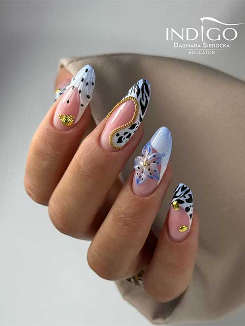 Animal print French manicure with zebra tips, cow patterns, gold studs, and a 3D flower on a nude base for a safari vibe.