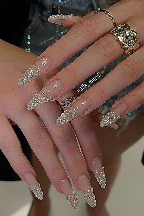 Dazzling nude almond nails featuring a clean base and clusters of rhinestones at the tips, blending sophistication with glamour. Dazzling nude almond nails featuring a clean base and clusters of rhinestones at the tips, blending sophistication with glamour.