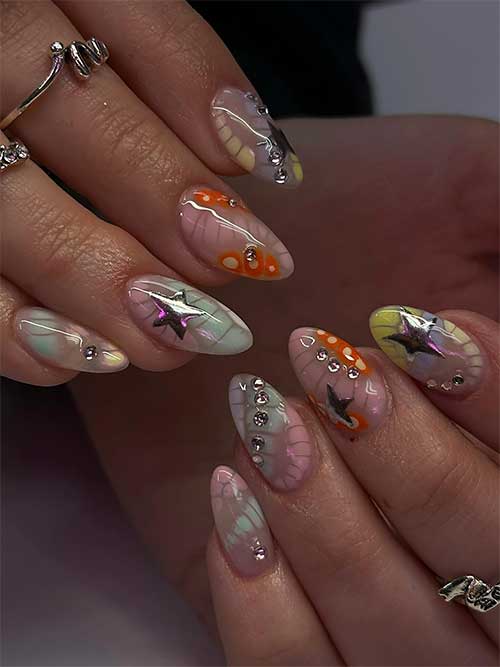 Dreamy pastel watercolor nails in almond shape, adorned with orange dots, silver stars, and sparkling rhinestones for a magical vibe.