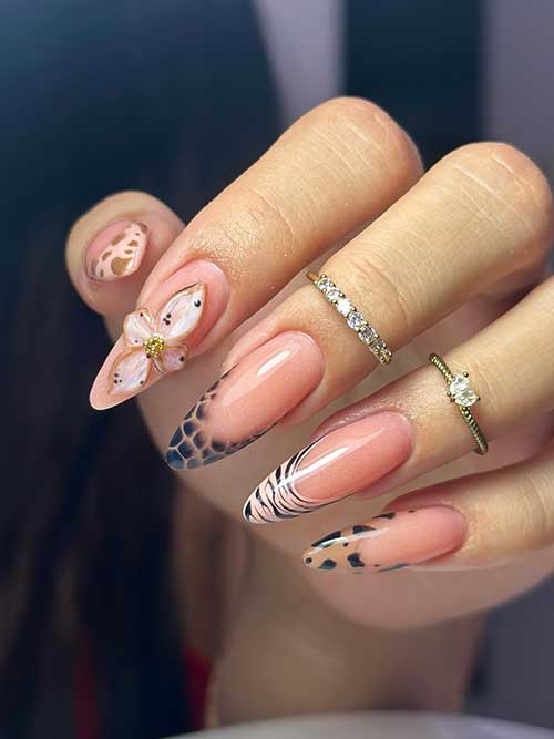 Elegant animal print French manicure with nude base, leopard and zebra designs, 3D flower, gold rings, and diamond accents.