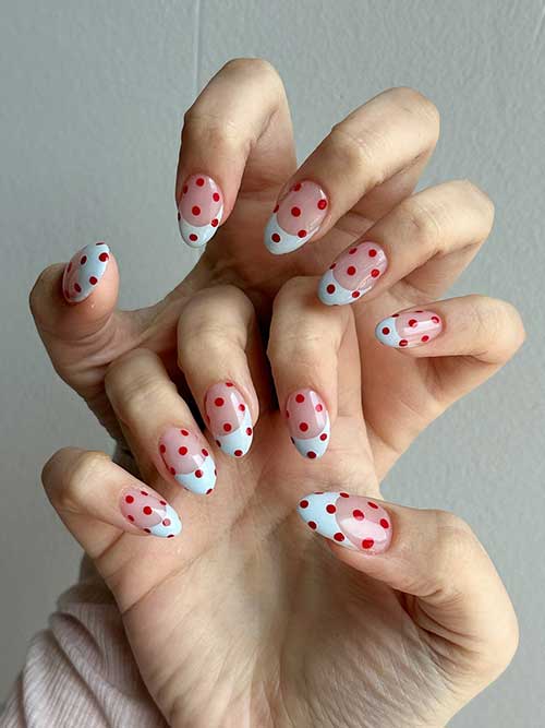 Light blue French tips with red dots on a sheer base create a fun and elegant nail design. Light blue French tips with red dots on a sheer base create a fun and elegant nail design.