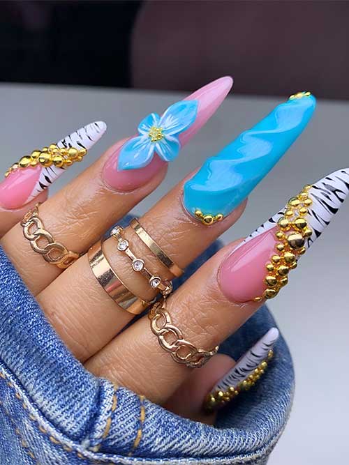 Luxurious stiletto animal print manicure featuring pink tips, zebra stripes, gold beads, a blue swirl, and a blue flower.