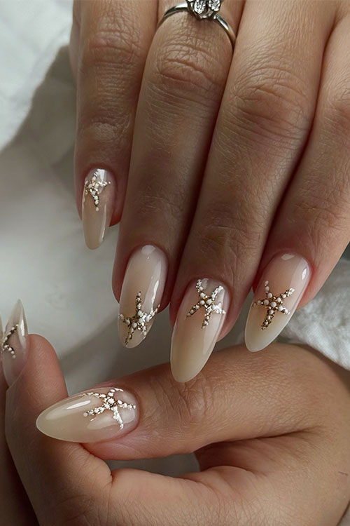 Nude almond nails with golden starfish accents, evoking a coastal escape and perfect for summer or beach weddings. Nude almond nails with golden starfish accents, evoking a coastal escape and perfect for summer or beach weddings.