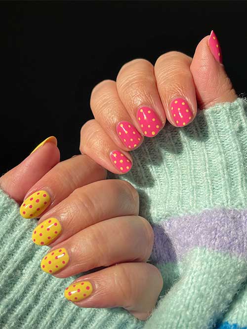 Pink nails with yellow dots on one hand, yellow nails with pink dots on the other, all in a chic, short rounded shape. Pink nails with yellow dots on one hand, yellow nails with pink dots on the other, all in a chic, short rounded shape.