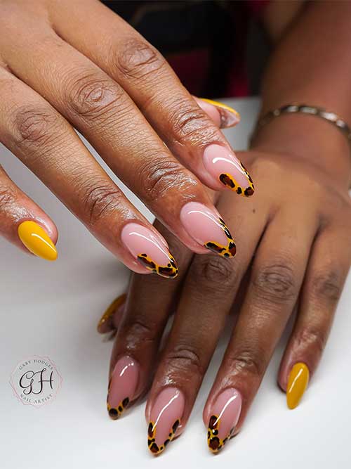 Stylish animal print French manicure with leopard print in yellow and brown, featuring mustard yellow accent nails on almond shapes.