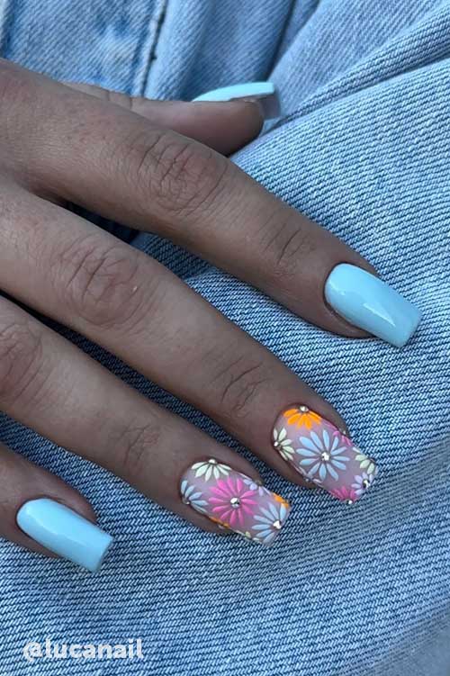 Light blue nails with two accent nails featuring delicate floral patterns of daisies in soft pink, white, yellow, and orange. Light blue nails with two accent nails featuring delicate floral patterns of daisies in soft pink, white, yellow, and orange.