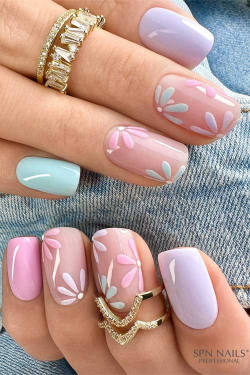 Pastel spring nails featuring soft blue, lavender, pink, and nude hues with floral patterns and gold rings for a chic look. Pastel spring nails featuring soft blue, lavender, pink, and nude hues with floral patterns and gold rings for a chic look.