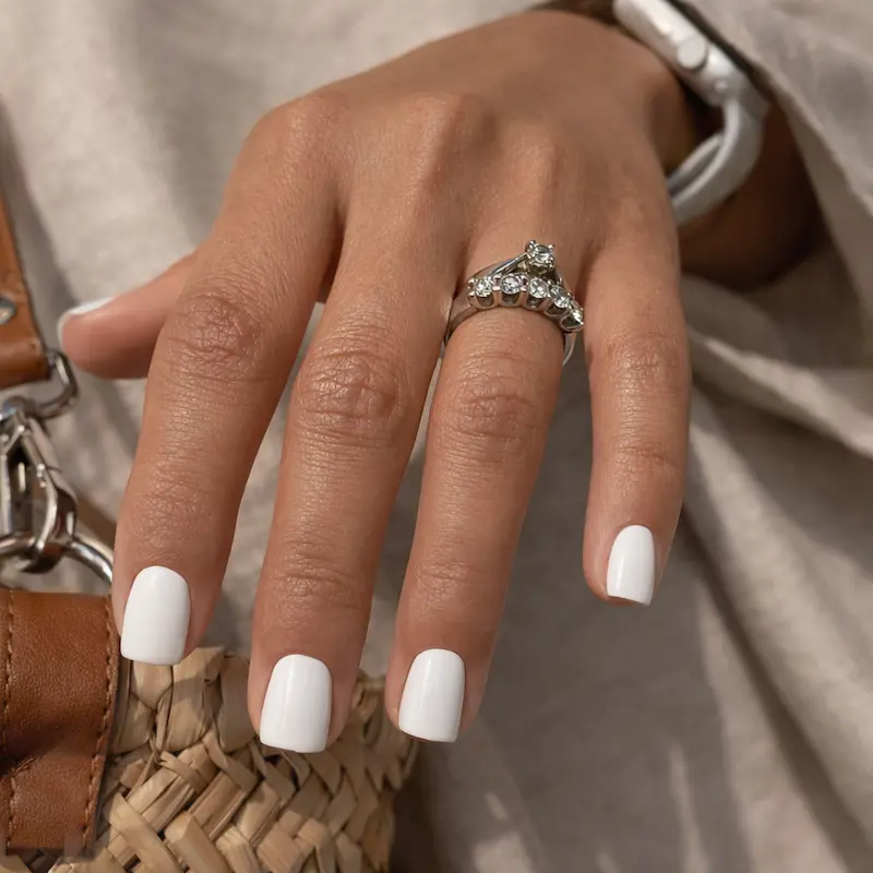 KASOICRA white matte short square press-on false nails applied on a womans hand against warm fabric