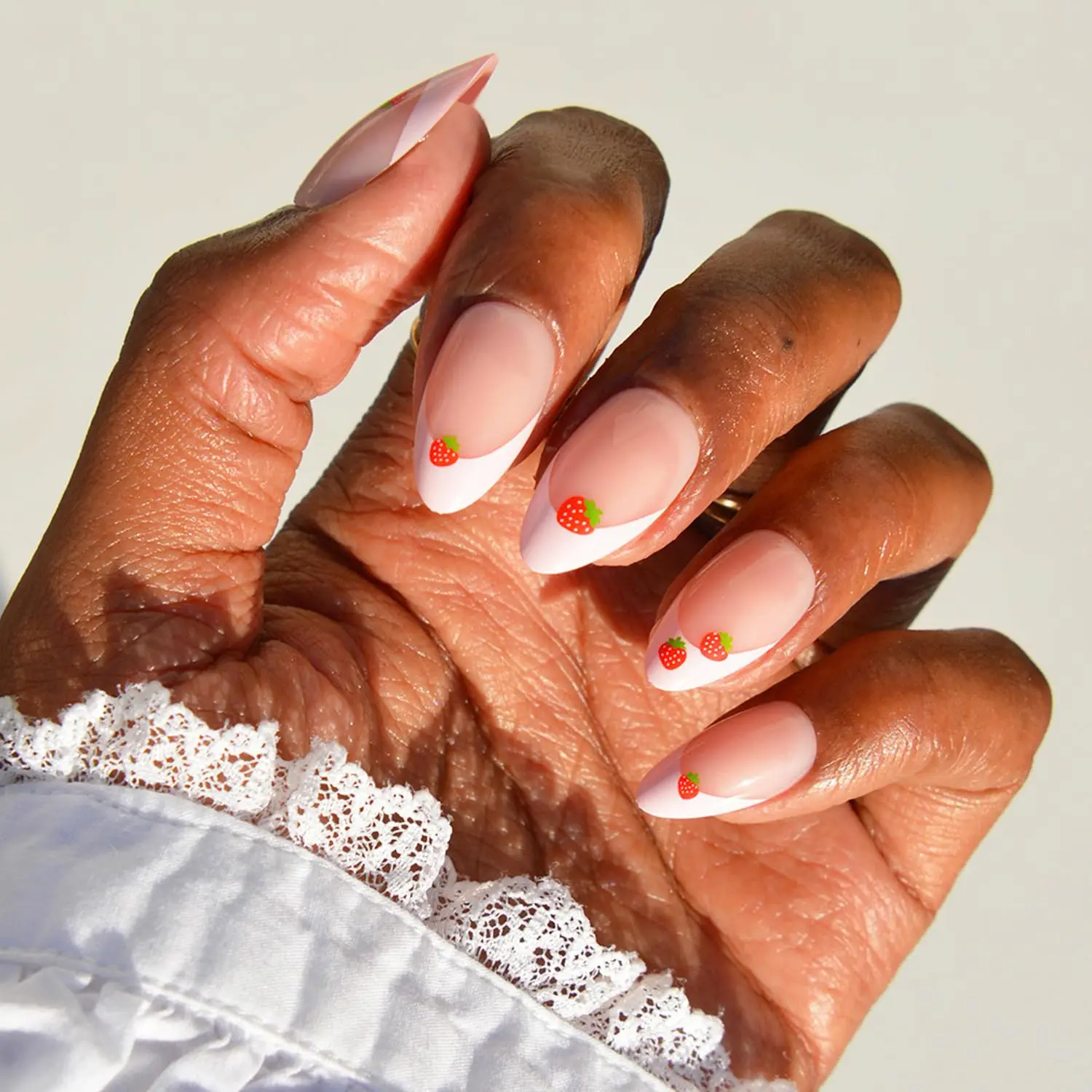 Glamnetic strawberry press on nails — glossy pink almond shape with a playful strawberry French tip